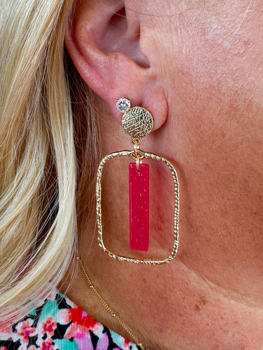 Rectangular hammered gold hoop earrings with transparent hot pink acrylic stick drop, designed by Taylor Shaye.