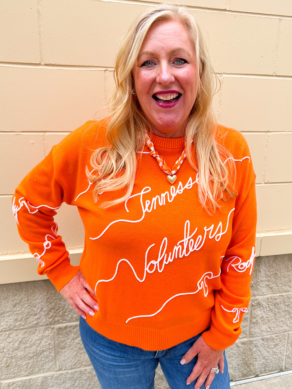 Orange merino wool blend Tennessee Volunteers script sweater featuring chain stitch embroidered hand-drawn collegiate artwork.