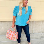 Light pink pleated top with puff sleeves and back tie details, styled for a breezy, feminine look.