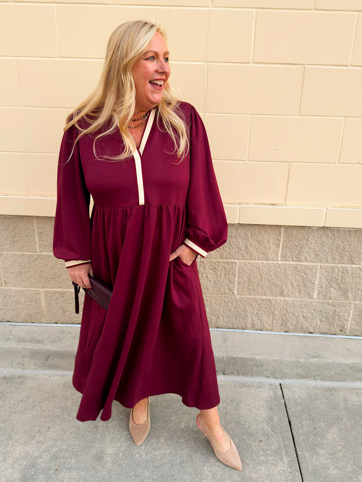 Garnet midi dress with cream contrast collar, puff sleeves, and side pockets on display.