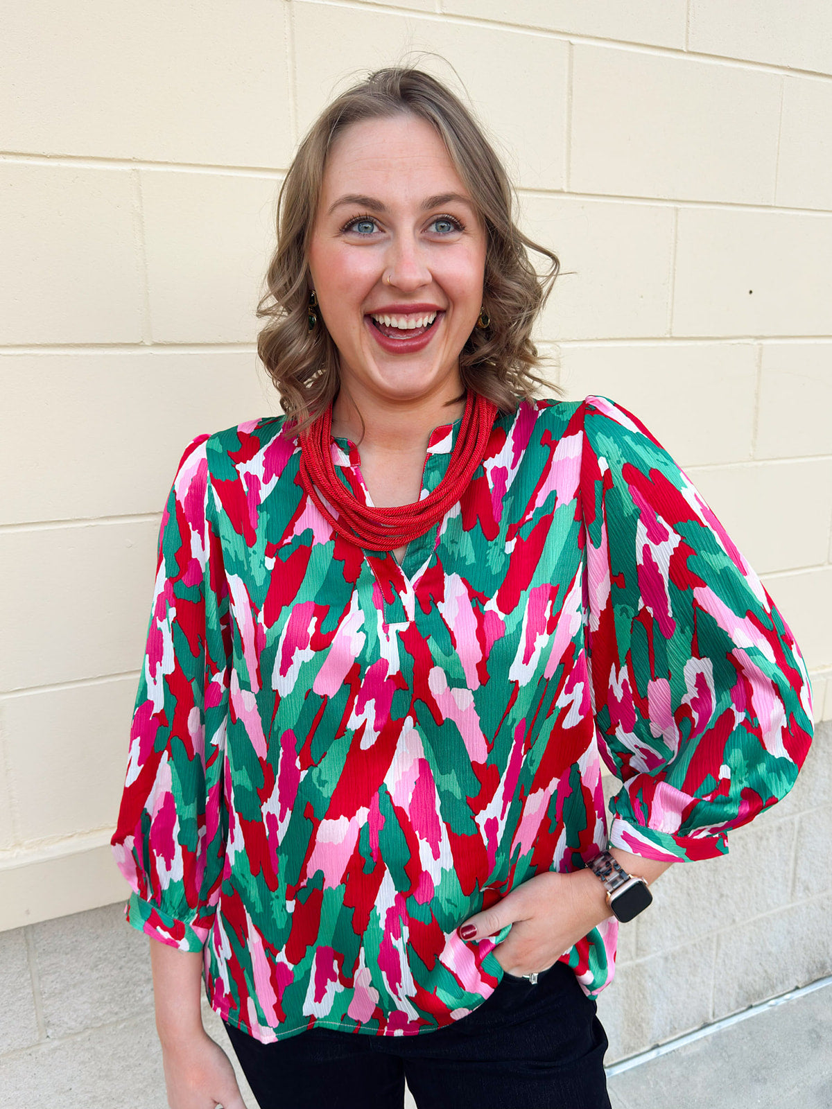 A feminine ruffled top with puff sleeves and an abstract floral print in red, pink, and green.