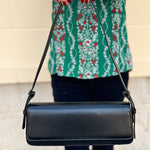 Matte black vegan leather shoulder bag with gold hardware and detachable strap.