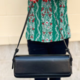 Matte black vegan leather shoulder bag with gold hardware and detachable strap.