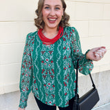 Green floral jacquard top with red and white pattern, V-neckline, puff sleeves, and smocked cuffs.