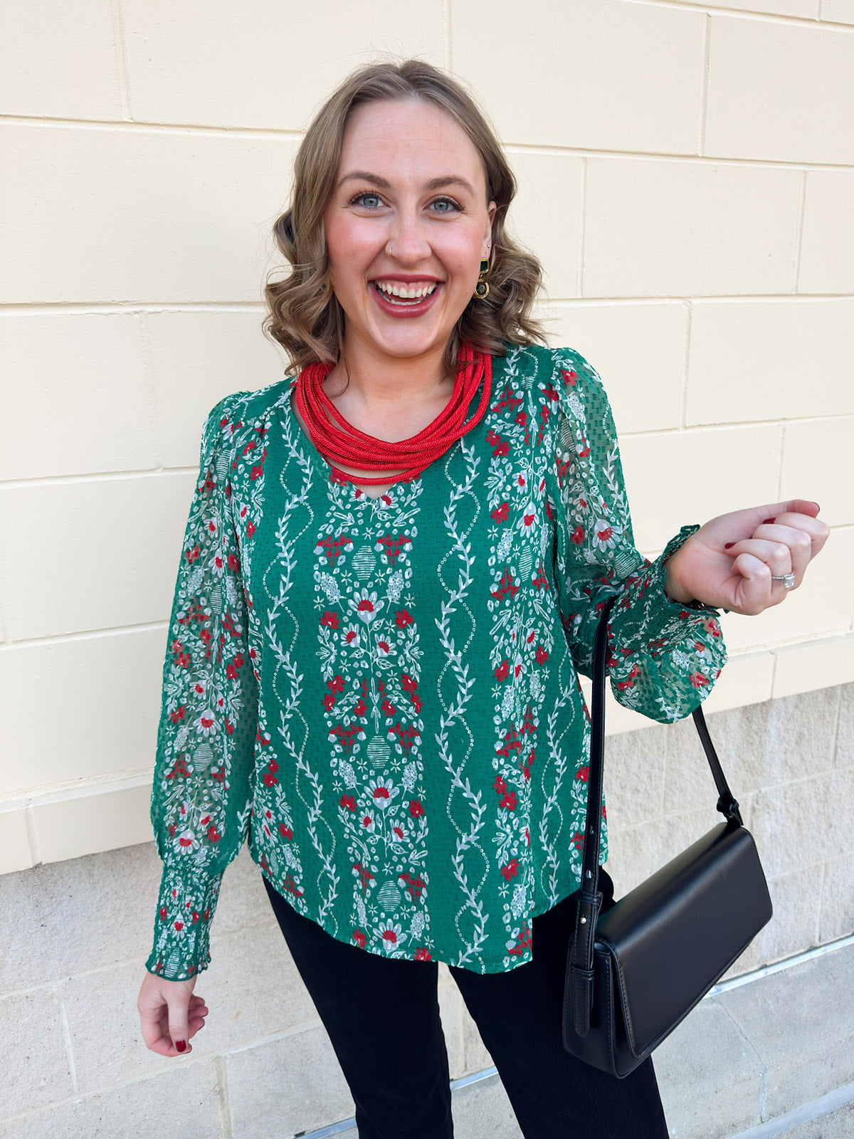 Green floral jacquard top with red and white pattern, V-neckline, puff sleeves, and smocked cuffs.