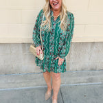 Green floral jacquard dress with red and white pattern, long sleeves, tiered hem, and tie neckline.