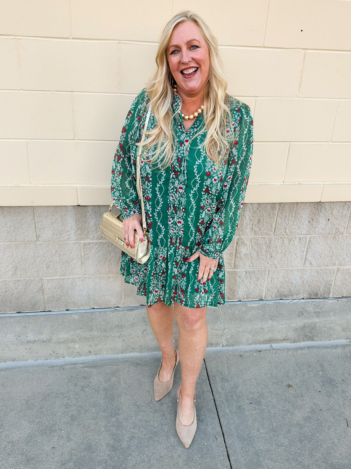 Green floral jacquard dress with red and white pattern, long sleeves, tiered hem, and tie neckline.