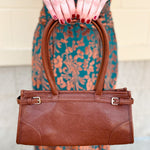 Brown structured vegan leather crossbody bag with gold hardware and top handles.