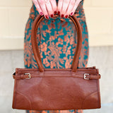 Brown structured vegan leather crossbody bag with gold hardware and top handles.