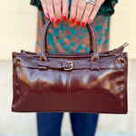 Chestnut brown vegan leather crossbody bag with gold hardware and buckle detail.