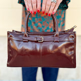 Chestnut brown vegan leather crossbody bag with gold hardware and buckle detail.