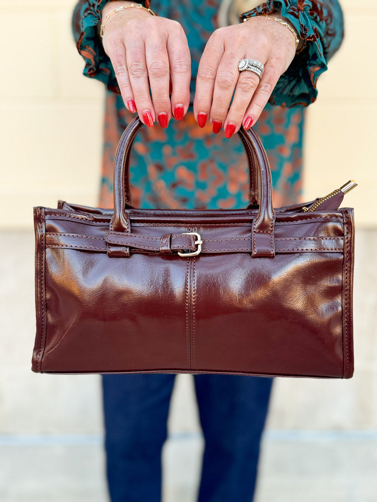 Chestnut brown vegan leather crossbody bag with gold hardware and buckle detail.