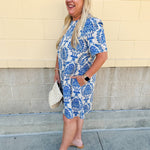 Blue and white damask print short-sleeve mini dress with pockets and back zipper closure, styled for a casual yet polished look.