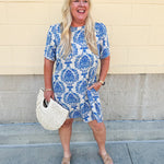 Blue and white damask print short-sleeve mini dress with pockets and back zipper closure, styled for a casual yet polished look.