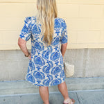 Blue and white damask print short-sleeve mini dress with pockets and back zipper closure, styled for a casual yet polished look.