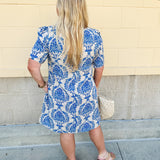 Blue and white damask print short-sleeve mini dress with pockets and back zipper closure, styled for a casual yet polished look.