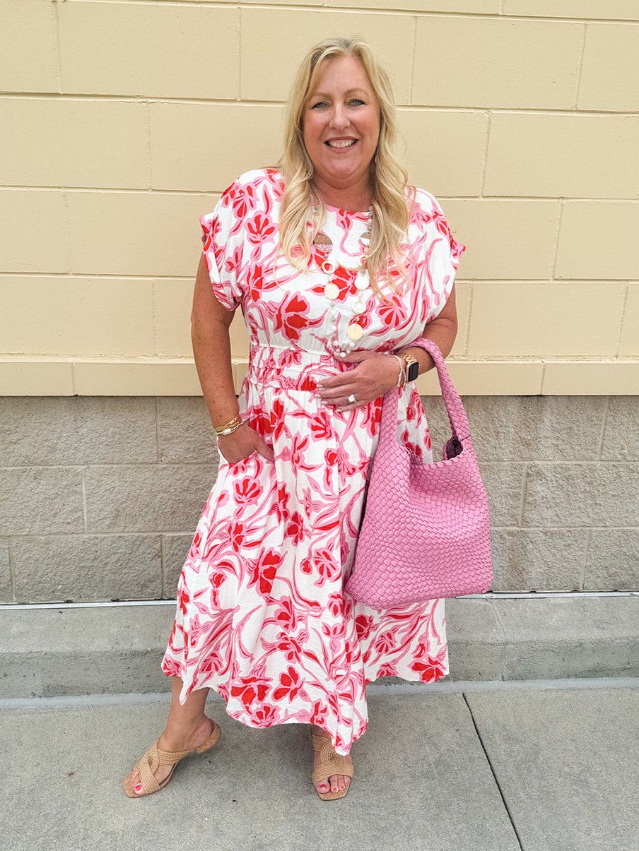 Woman wearing a drop shoulder midi dress styled for a summer event; elegant and feminine boutique outfit.