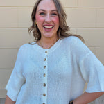 White long-sleeve knit sweater with contrasting brown buttons