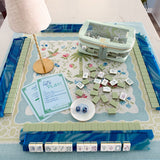 Palm Garden Estate Luxury Mahjong Tablescape featuring Willow Mahjong Tiles, Blue Lace Agate racks, Palm Garden Estate mat, lamp, dice, and storage bag.