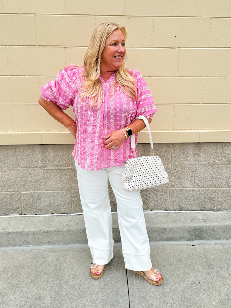 Pink cotton top with cream floral embroidery, ruffled v-neckline, and puff sleeves