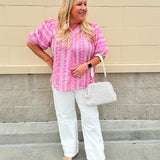 Pink cotton top with cream floral embroidery, ruffled v-neckline, and puff sleeves