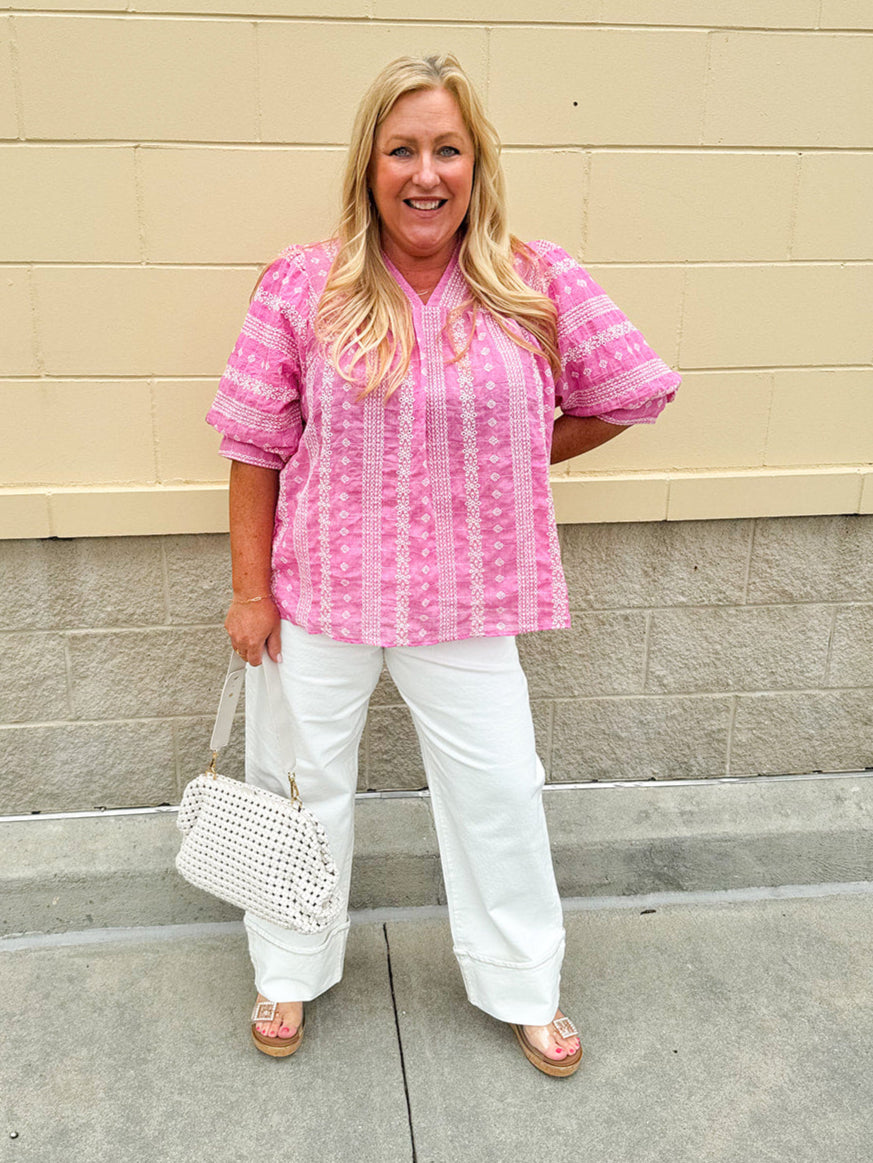 Pink cotton top with cream floral embroidery, ruffled v-neckline, and puff sleeves