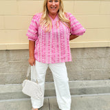 Pink cotton top with cream floral embroidery, ruffled v-neckline, and puff sleeves