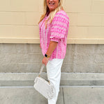 Pink cotton top with cream floral embroidery, ruffled v-neckline, and puff sleeves