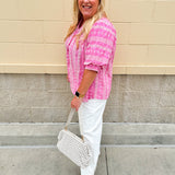 Pink cotton top with cream floral embroidery, ruffled v-neckline, and puff sleeves