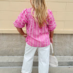 Pink cotton top with cream floral embroidery, ruffled v-neckline, and puff sleeves