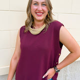 Women's wine sleeveless sweater vest featuring gold-accented buttons, front pockets, and a lightweight knit design.