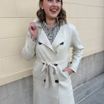 Long cream winter coat with double collar, decorative buttons, and cuffed sleeves.