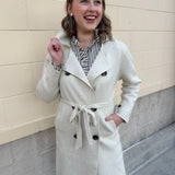Long cream winter coat with double collar, decorative buttons, and cuffed sleeves.