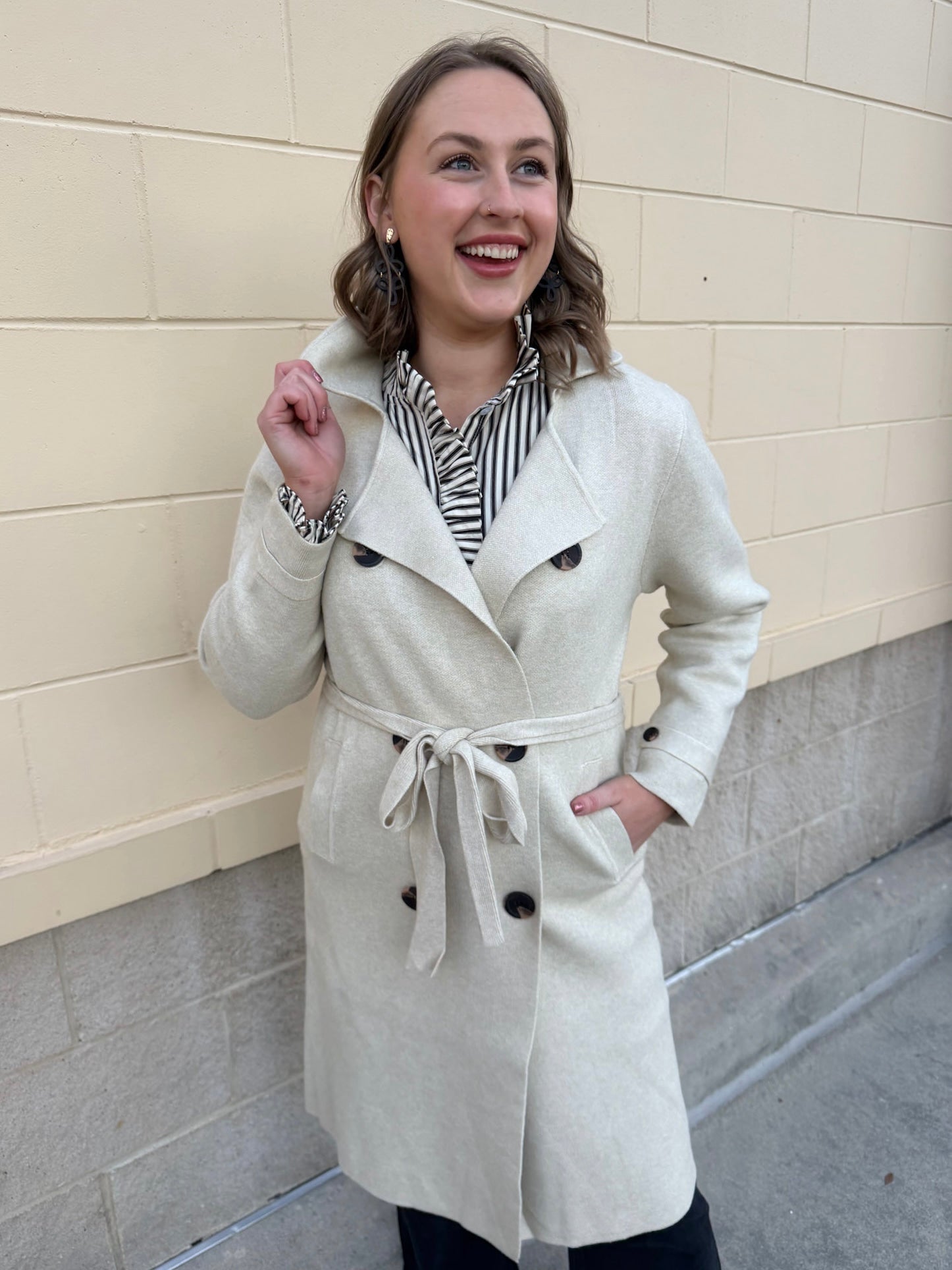 Long cream winter coat with double collar, decorative buttons, and cuffed sleeves.