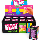 Translucent gummy bear squish toy available in orange, purple, and blue with a soft stretchy texture and glossy candy-inspired finish.
