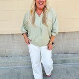 Sage green V-neck loose-fit blouse with pleated cuffed sleeves, styled for a fresh and effortless look.