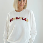 White cropped fleece crewneck sweatshirt with alternating garnet and gold chenille “Seminoles” lettering across the chest.