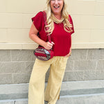 Clear football-shaped crossbody bag with garnet trim, zipper closure, and adjustable straps.