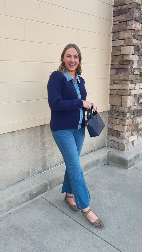 Navy blue long-sleeve sweater jacket with a denim collar, denim center-front trim, and gold buttons.
