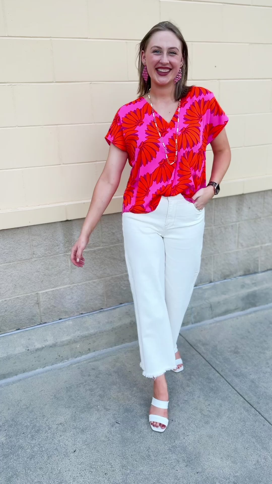 Banana and floral print top in orange and hot pink with V-neck and short dolman sleeves, displayed on hanger against neutral background