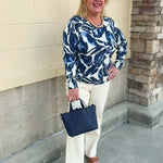 White textured long-sleeve sweater top with navy and light blue leafy designs.