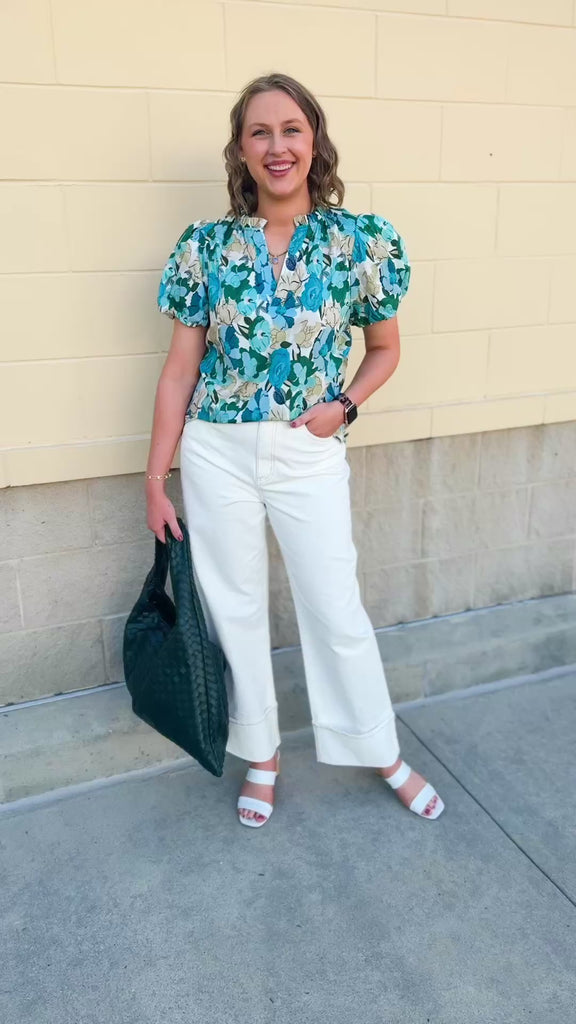 Blue floral blouse with pink accents, featuring a ruffle-trimmed split neckline and short puff sleeves