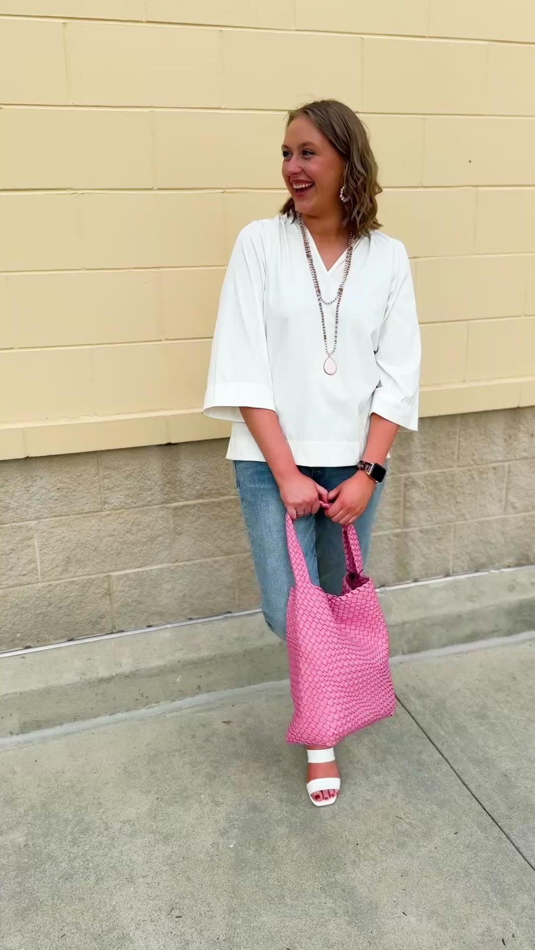 White blouse with ruffled V-neck and ¾ length wide sleeves, styled for a feminine, polished look.