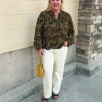 Spiced Botanical Blouse featuring a dark green base, intricate orange, red, green, and beige floral and swirl print, long sleeves, and a tie neckline.
