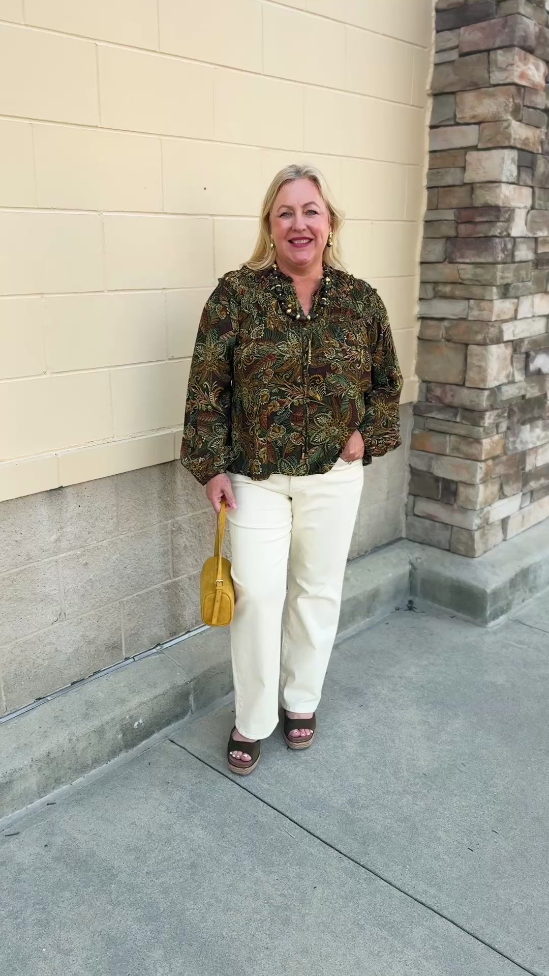 Spiced Botanical Blouse featuring a dark green base, intricate orange, red, green, and beige floral and swirl print, long sleeves, and a tie neckline.