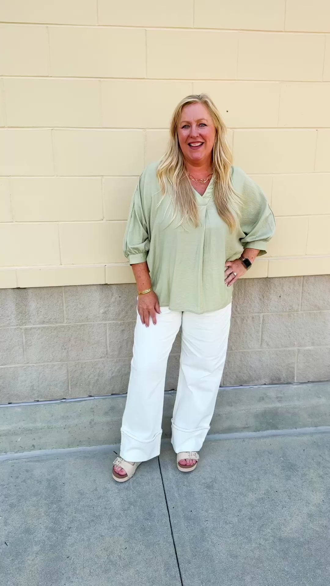 Sage green V-neck loose-fit blouse with pleated cuffed sleeves, styled for a fresh and effortless look.