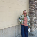 Painted Woodland Jacket featuring an olive, green, blue, and orange botanical print on a white background, a collared neckline, loop button closures, long sleeves, side pockets, and a cropped boxy silhouette.