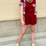 Garnet knit romper with white contrast trim on neckline, sleeves, and chest pocket. Features half sleeves, elastic waist, and keyhole back—sporty and stylish.