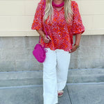 Pink and orange paisley print blouse with frilled tie neckline and three-quarter peasant sleeves against a neutral background