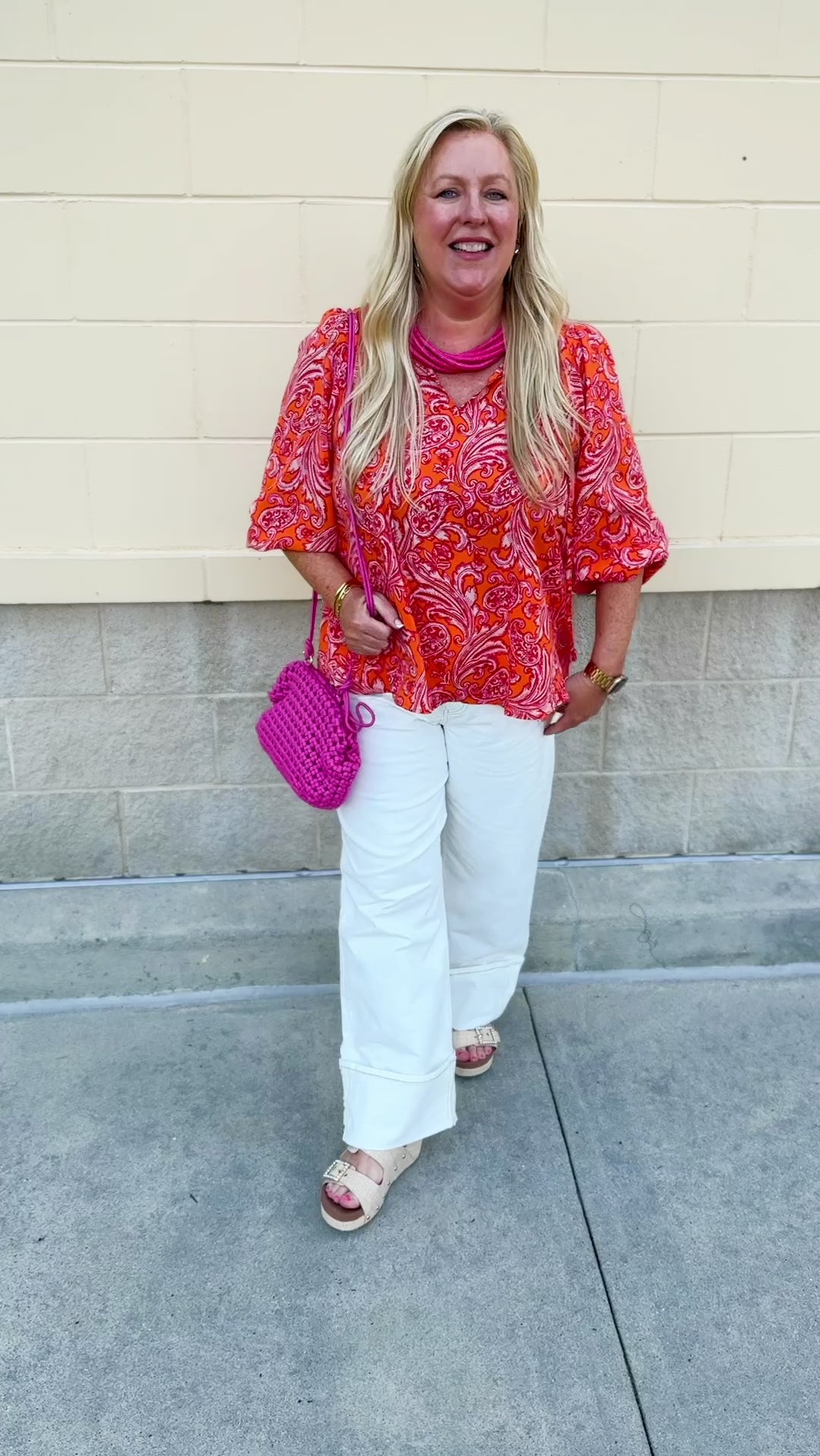 Pink and orange paisley print blouse with frilled tie neckline and three-quarter peasant sleeves against a neutral background